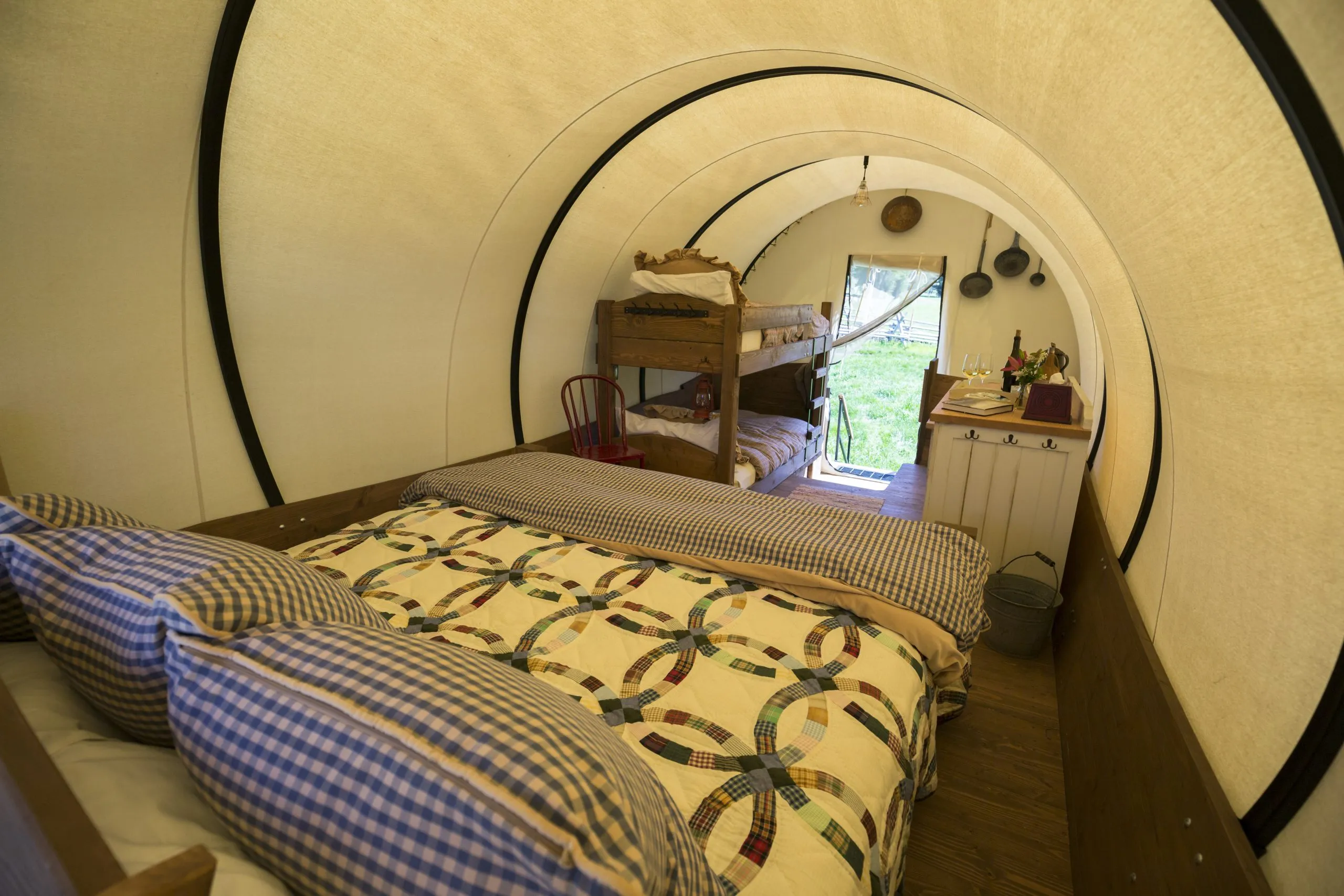Interior of a covered wagon room looking towards the open entrance from the bed's point of view