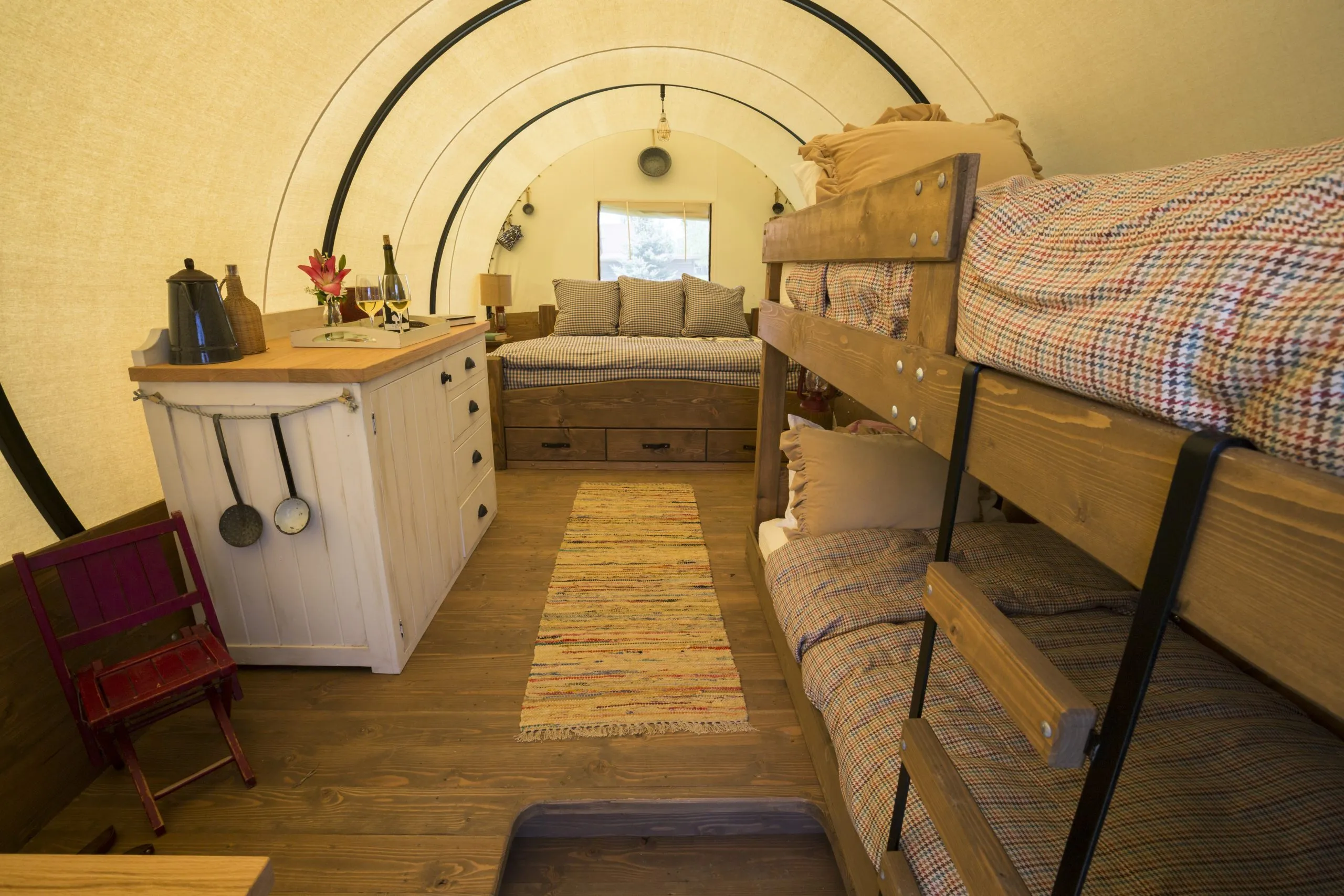 Interior of a covered wagon with bunk beds and a large bed at the end