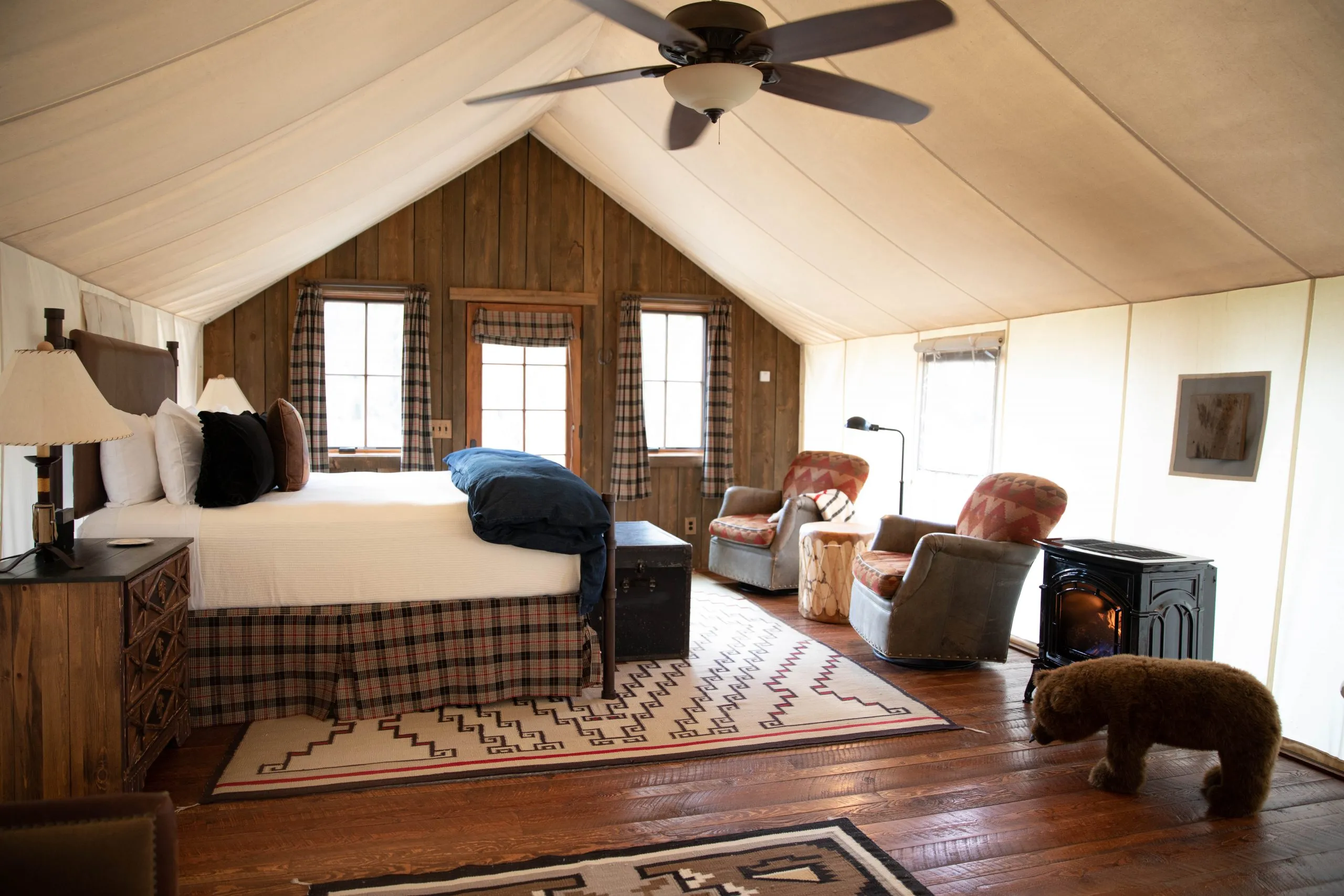 Bedroom inside a tented cabin space with a ceiling fan and portable fireplace