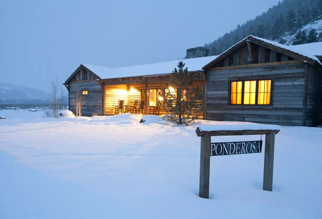 A cabin covered in snow with a sign that reads 