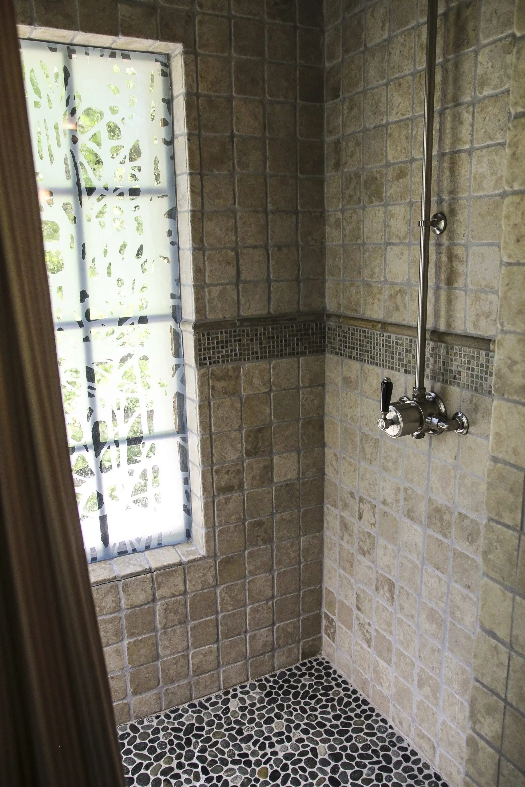 A tiled shower with a frosted window in the side of the wall
