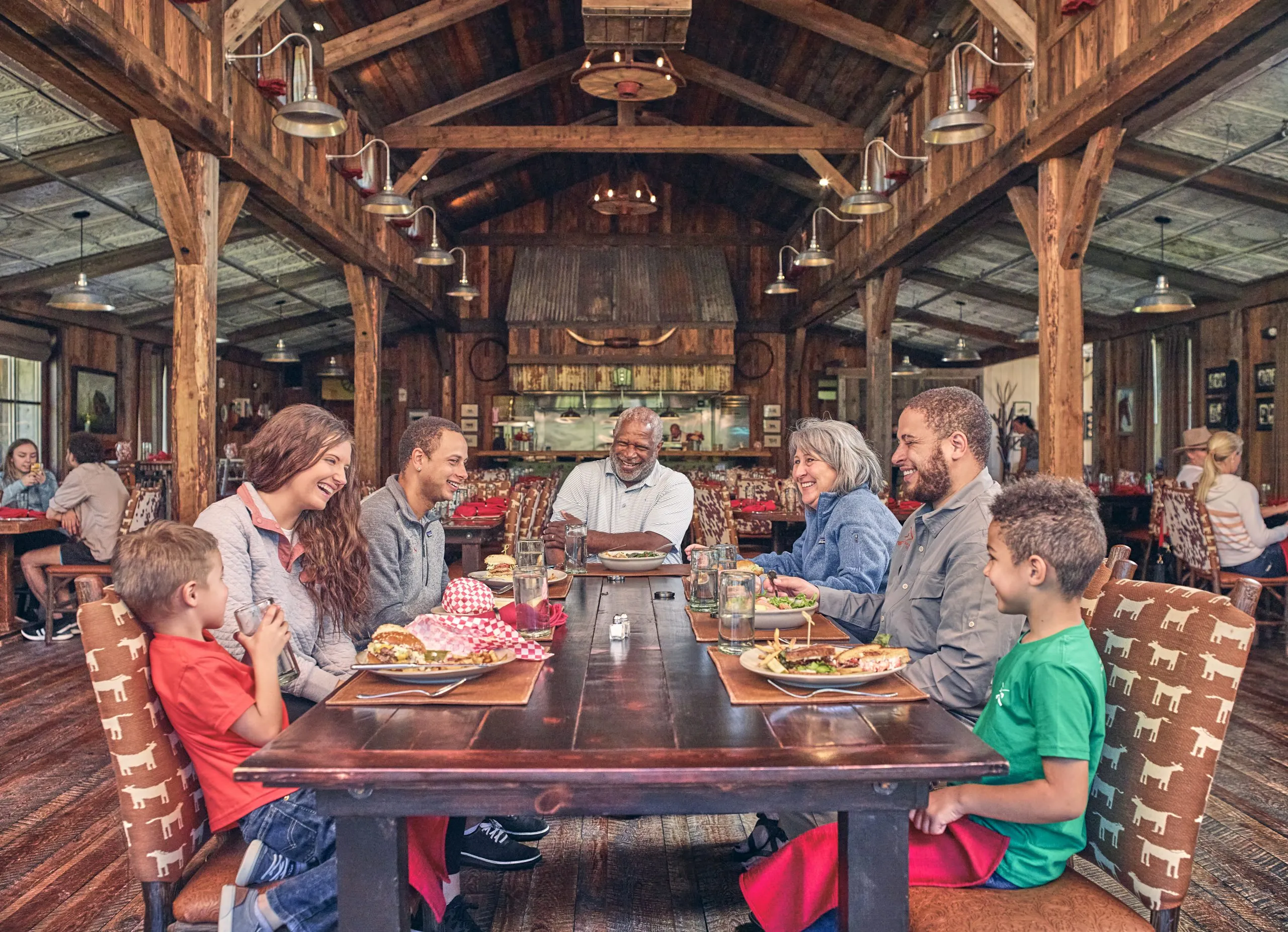A family of seven having dinner around a large rectangular wooden table in a restaurant