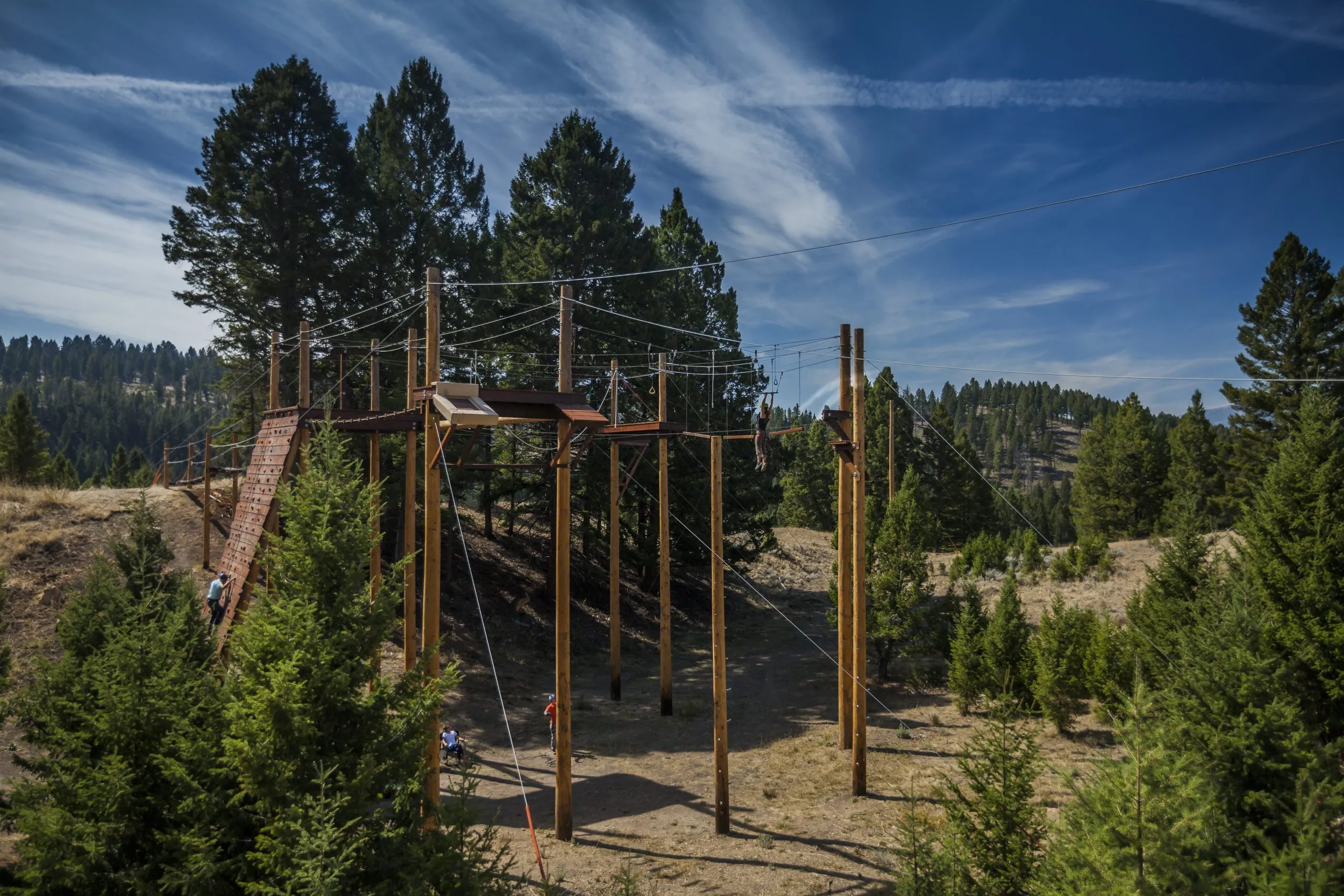 Rope course suspended high in the air with people interacting with it