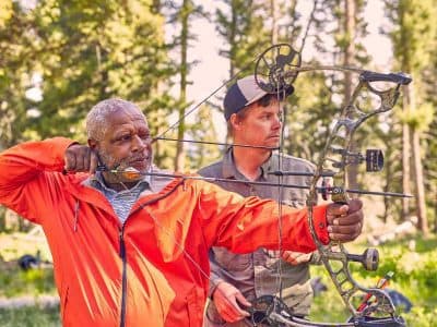 Two men in forrest with bows