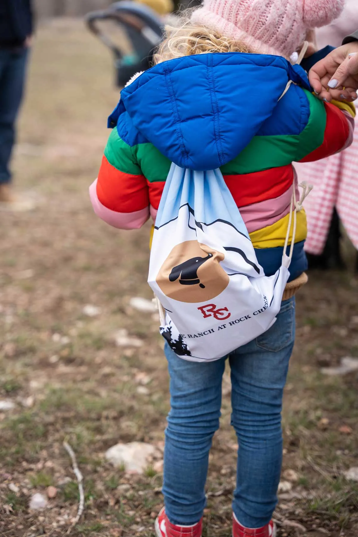 Boy wearing a colorful jacket with a Ranch at Rock Creek back pack