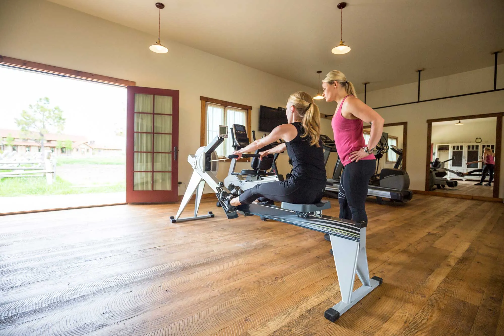 Woman on rowing machine in gym with trainer