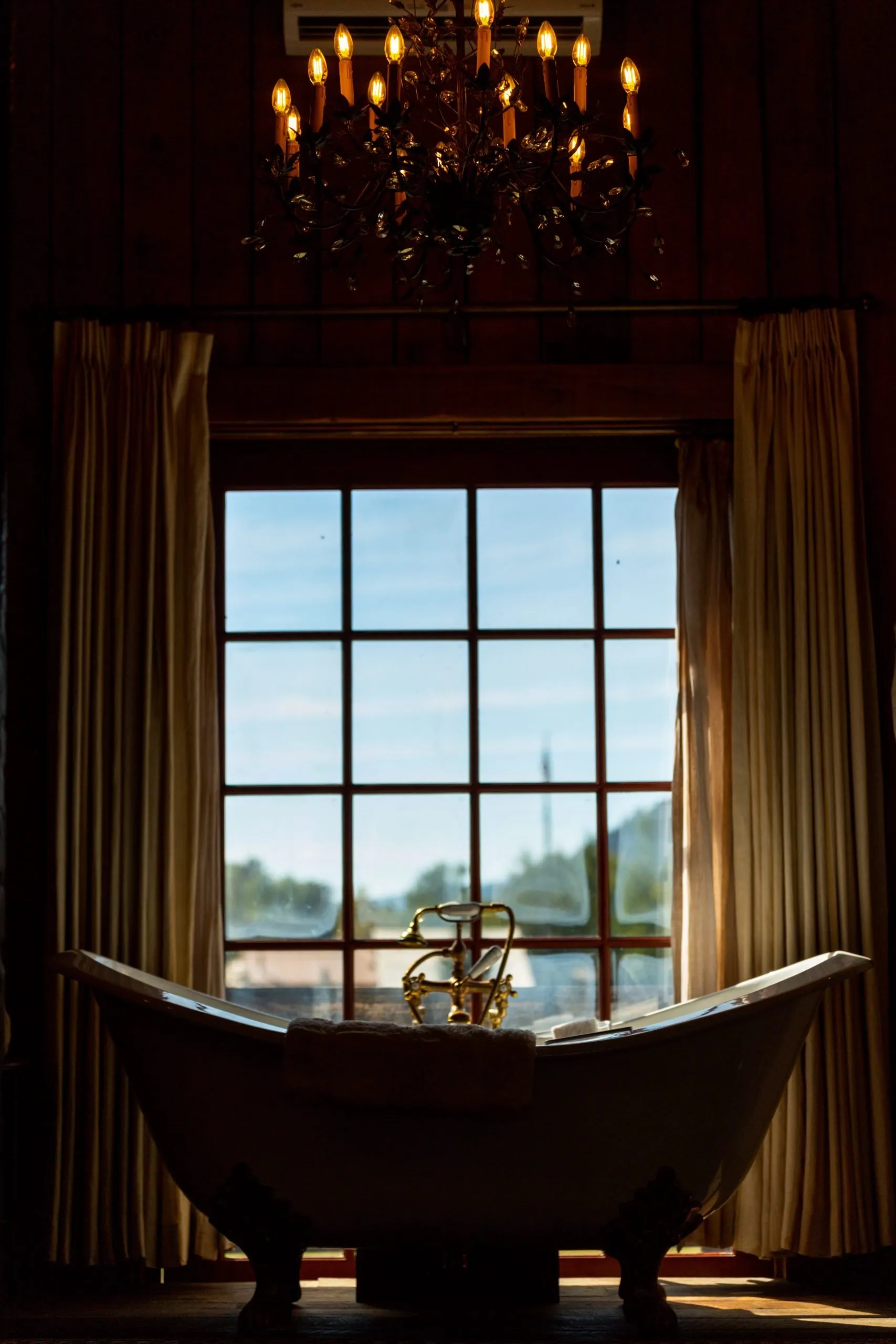 A luxurious bath tub facing a window with open curtains to the sides