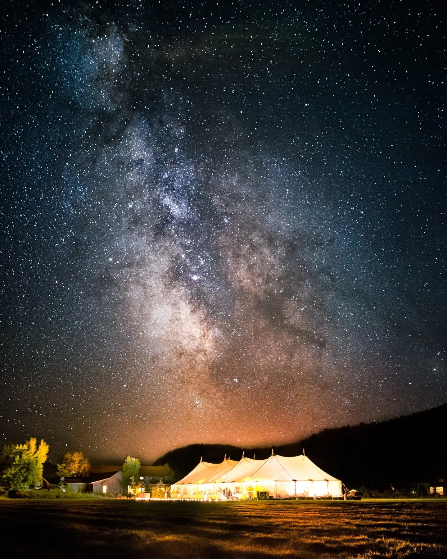 A starry night sky with a large lit up tent