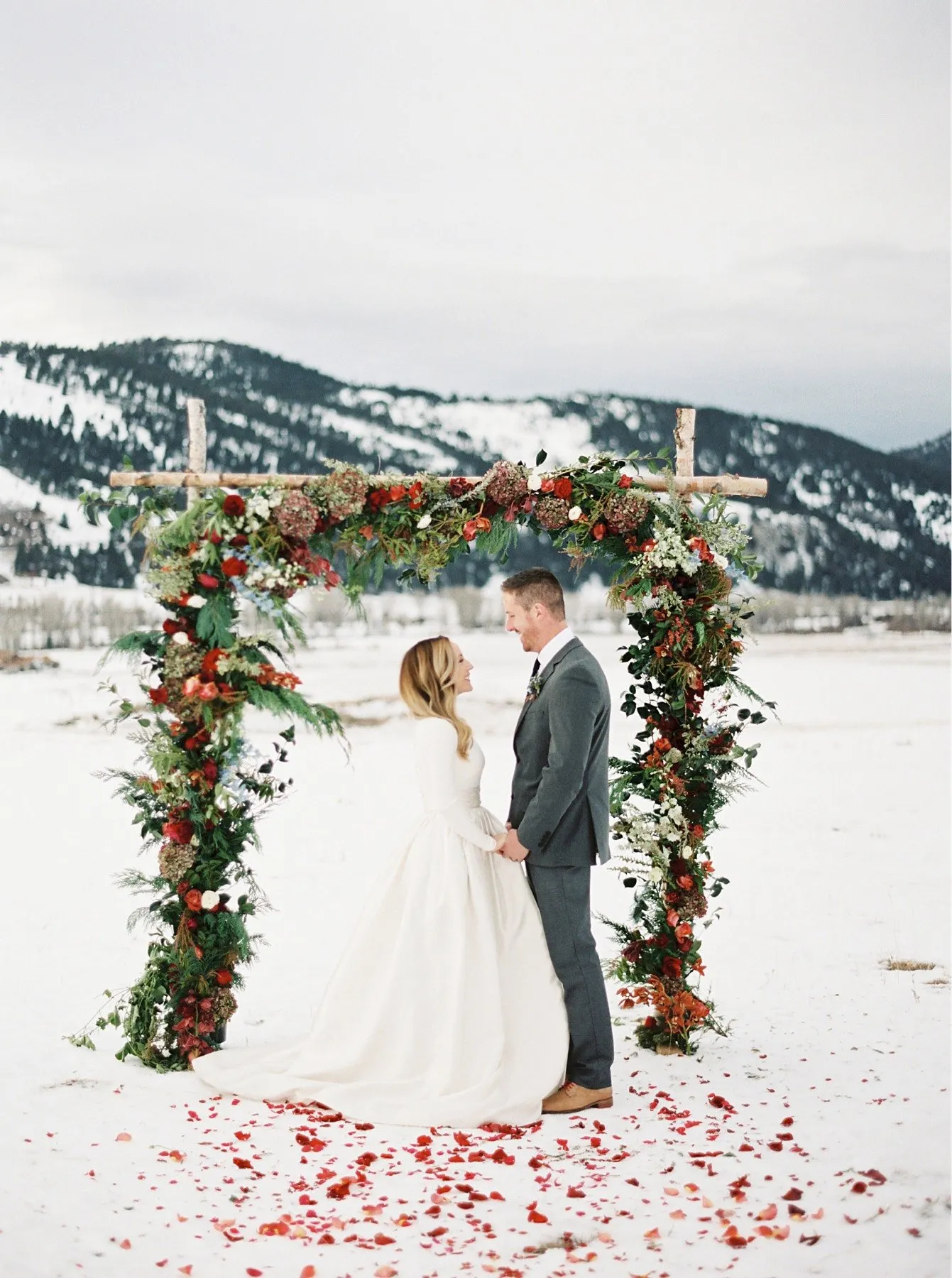 Bride and groom in a snowy field under an arch