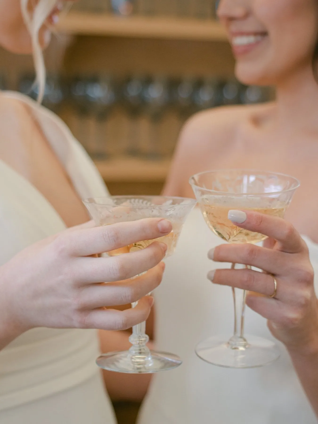 Close up of two glasses touching in two brides' hands