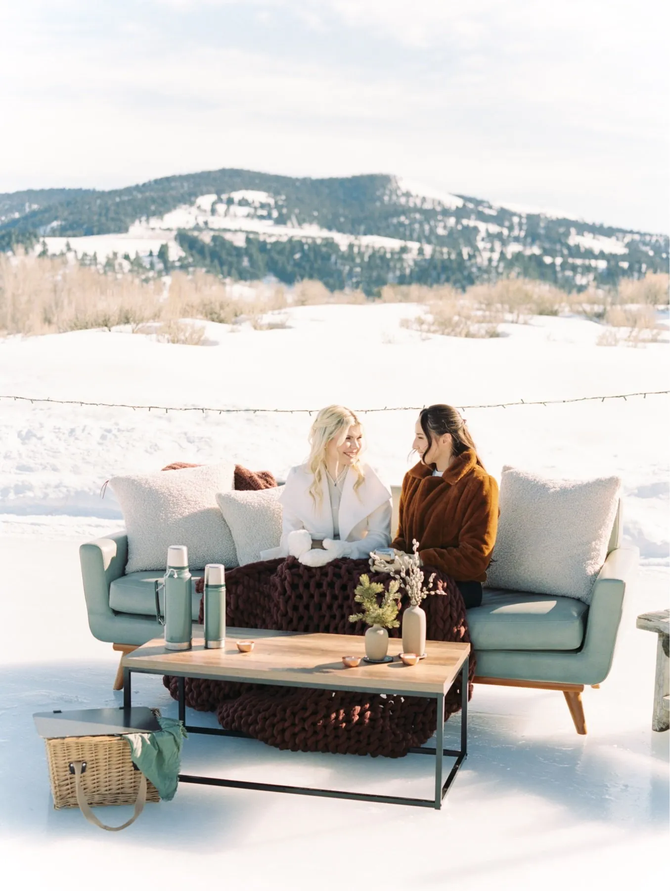 Two women seated on a couch in the snow