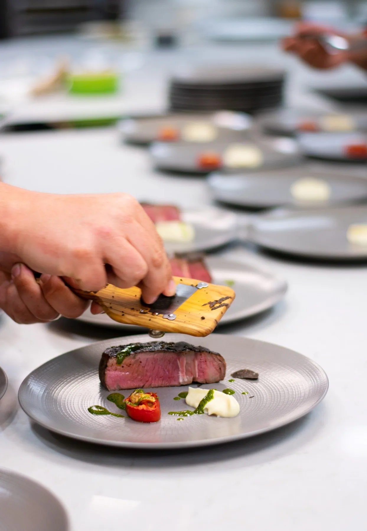 A chef garnishes a plate of steak
