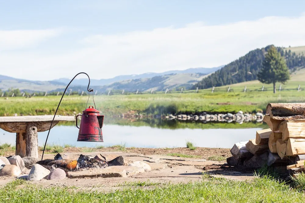 A kettle over a fire in front of a pond