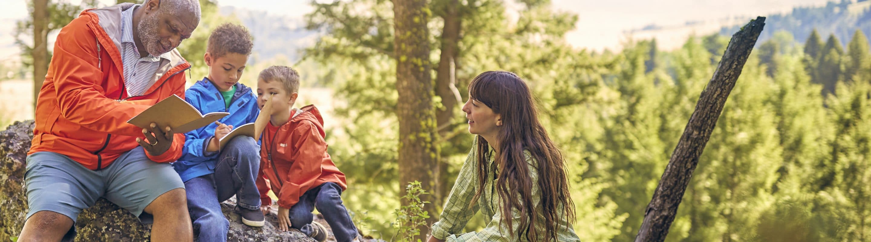 A family sits in the woods and writes in journals