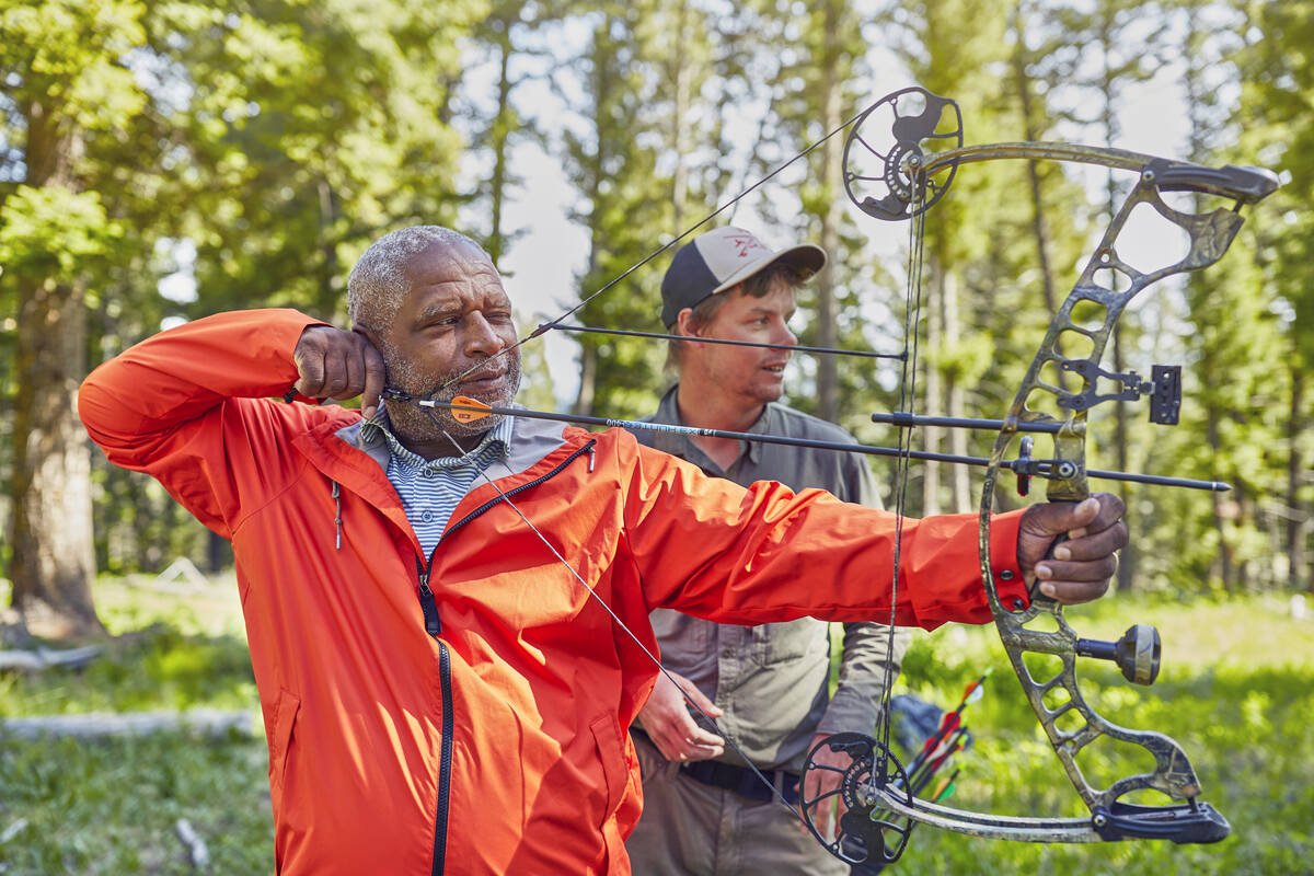 a man holding a bow and arrow and a man watching